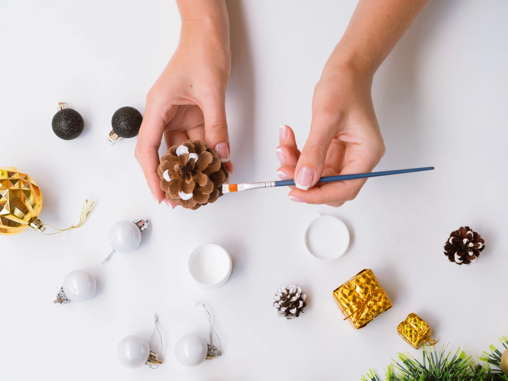 Malowanie elementów do stroika świątecznego podczas warsztatów artysrtycznych